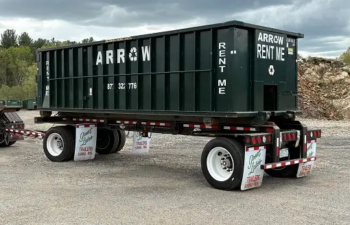 Green hook lift dumpster with "ARROW RENT ME" signage, suitable for residential and commercial projects, positioned on a trailer in a construction site setting.